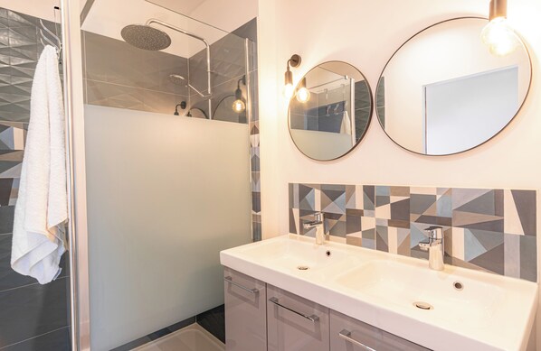 A modern bathroom with a shower, two sinks, and a mirror.