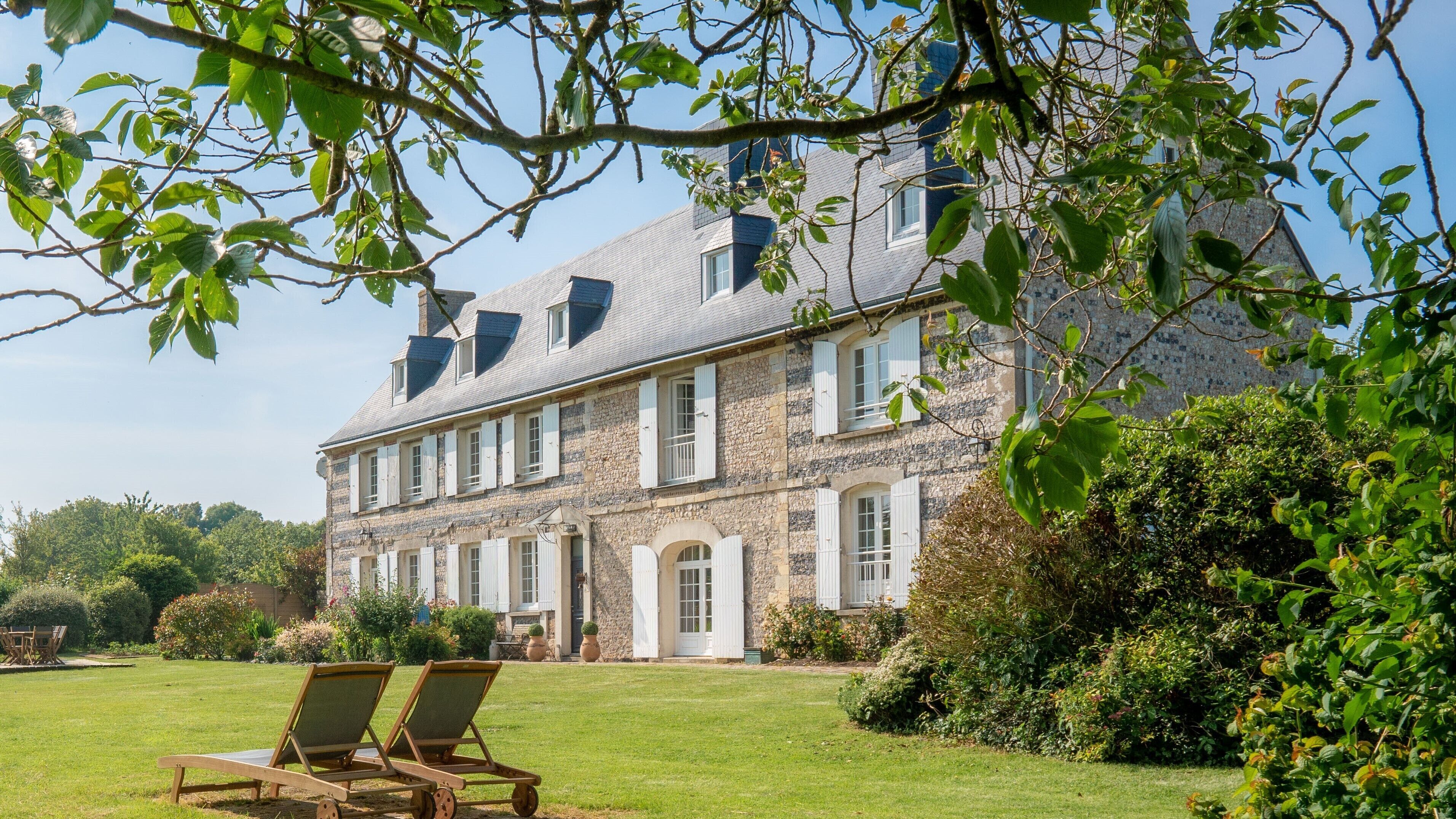 A stone building with multiple windows and a well-maintained lawn.