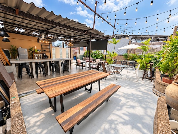 Un área de patio al aire libre con barra, asientos y luces colgantes.