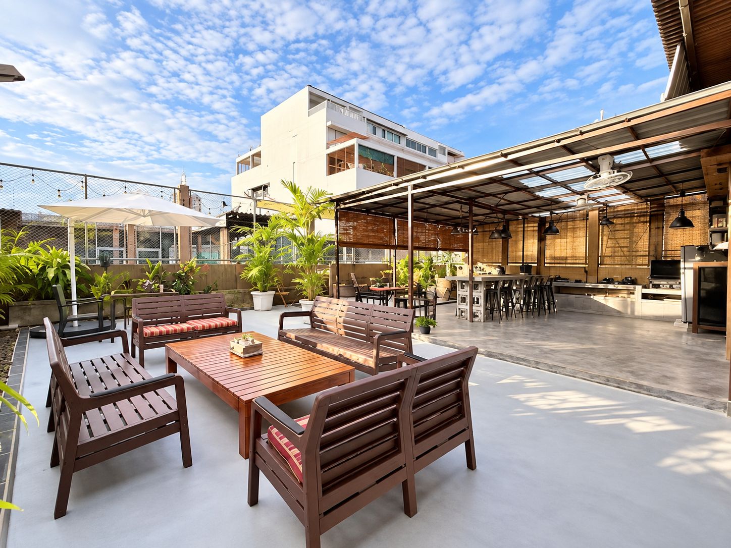 An outdoor patio with wooden furniture, a grill station, and potted plants.