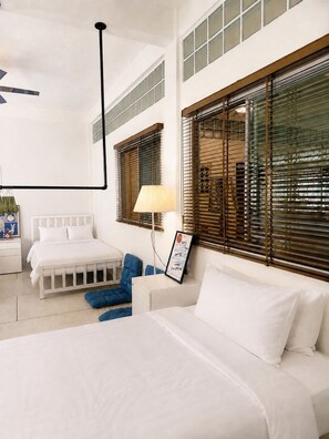A hotel room with a large bed, a desk with a lamp, and two chairs. - Yaimak House Mid Century (Bangkok)