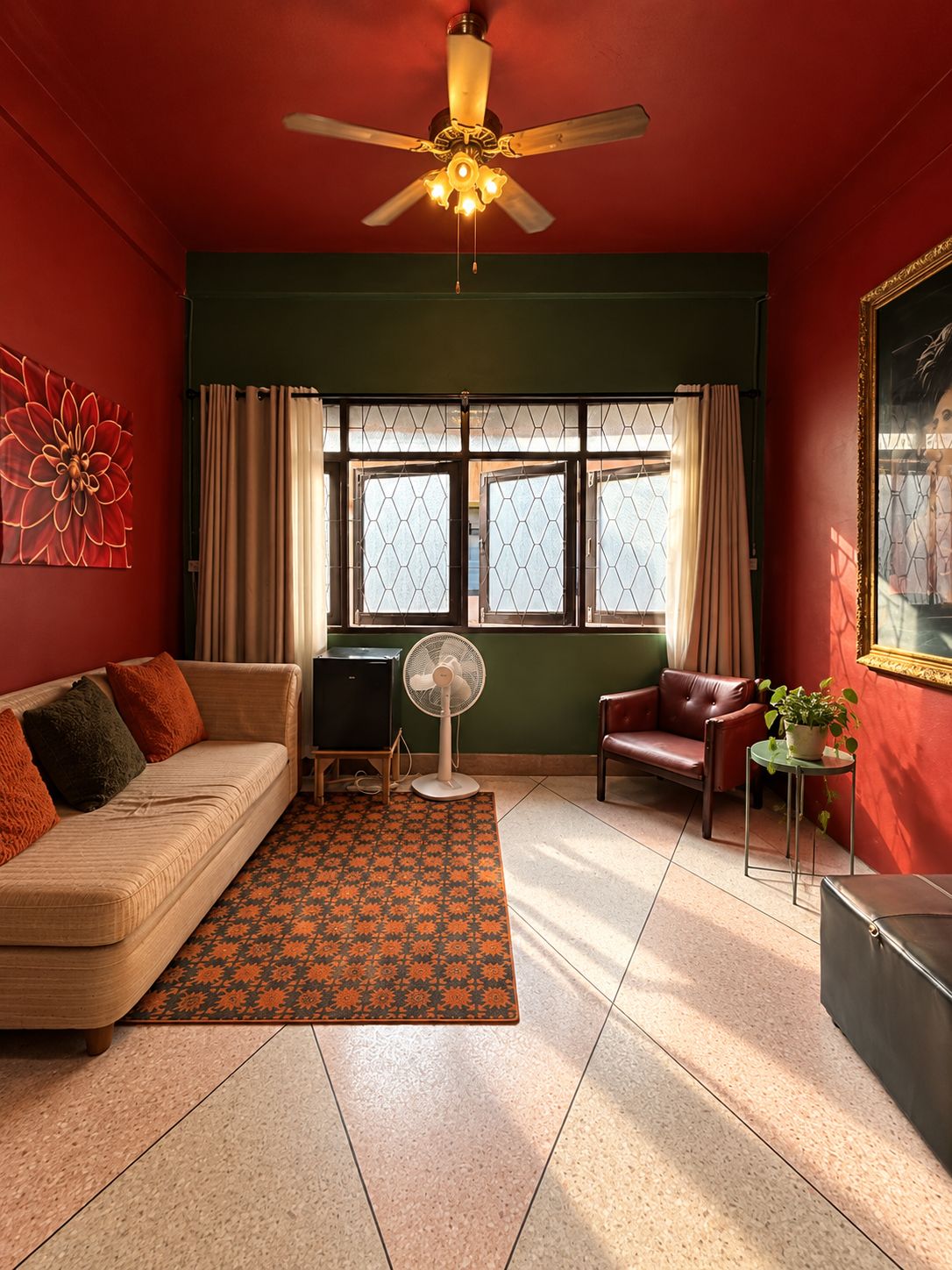 A room with a ceiling fan, a sofa, a chair, a small table with a plant, and a window with curtains.