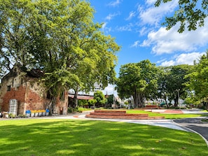 Un parque con una estructura de piedra circular, árboles y un edificio de fachada de ladrillo.