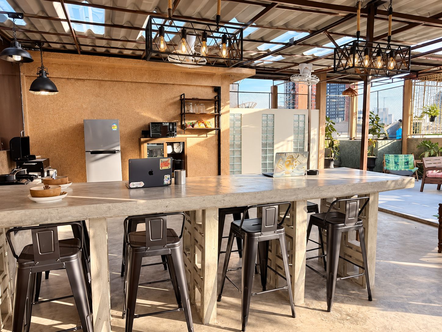 A modern kitchen with a bar area, bar stools, and a laptop on the counter.