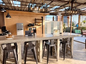 A modern kitchen with a bar area, bar stools, and a laptop on the counter. - Yaimak House Mid Century (Bangkok)