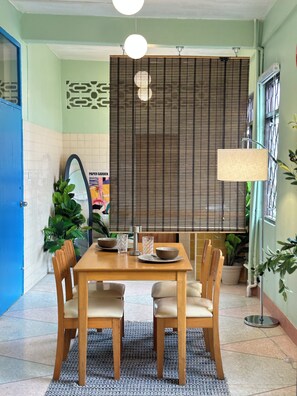 A dining area with a wooden table, chairs, a patterned rug, and a decorative wall with a poster. - Yaimak House Mid Century (Bangkok)