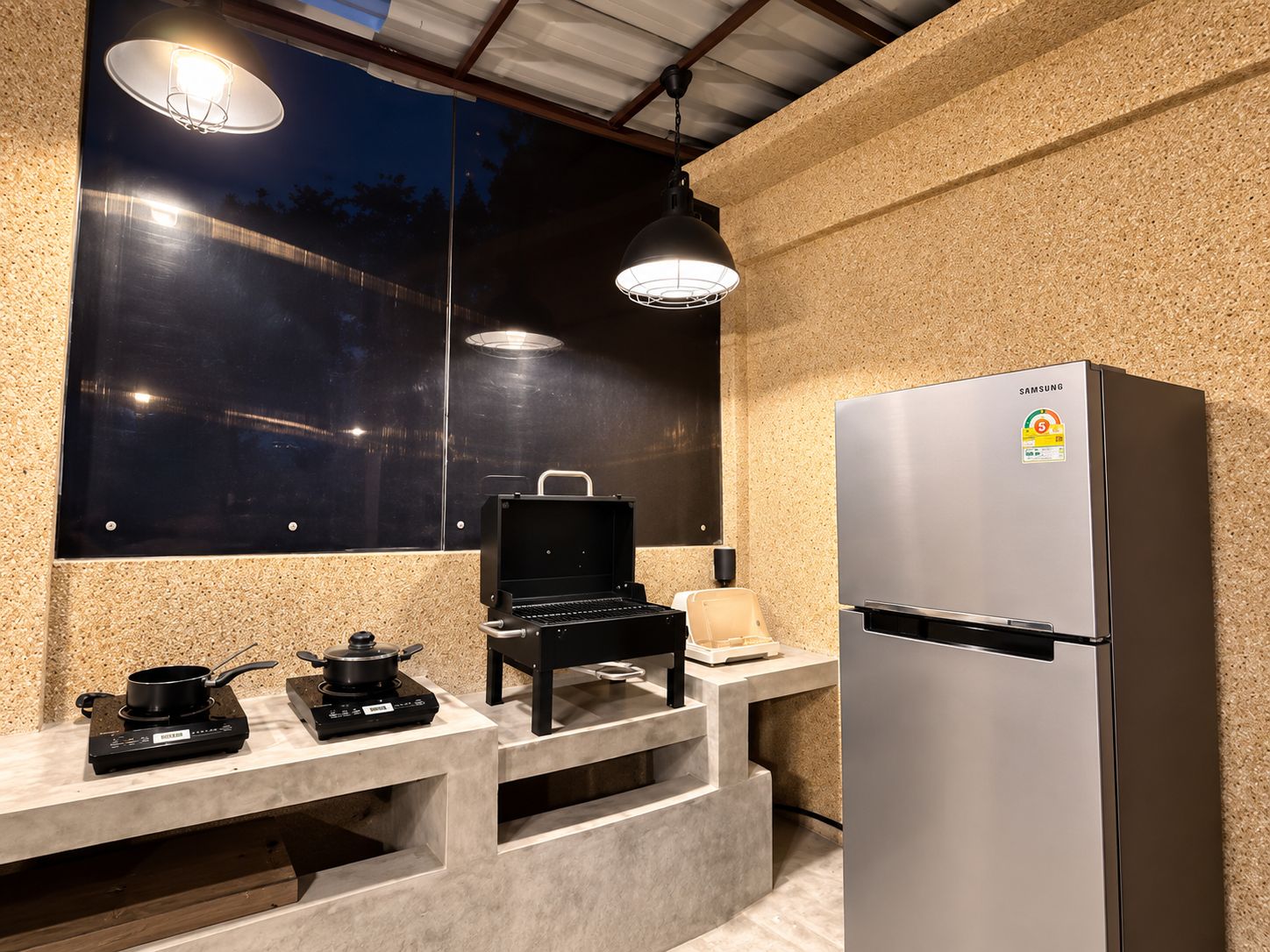 Una cocina compacta con un refrigerador de acero inoxidable, una estufa a gas portátil y un microondas.