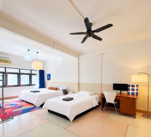 A hotel room with two beds, a desk, a chair, a desk lamp, a ceiling fan, and a window with a view. - Yaimak House Mid Century (Bangkok)