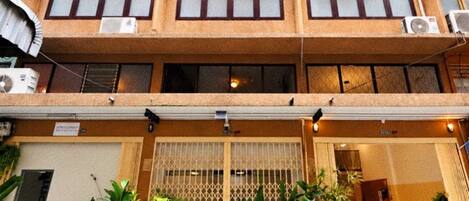 A multi-story building with balconies, potted plants, and a gated entrance.