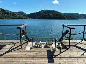A wooden deck with exercise equipment overlooking a calm lake and forested hills.