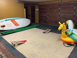 Une pièce avec un tapis vert, une planche de surf gonflable blanche et un animal gonflable jaune.