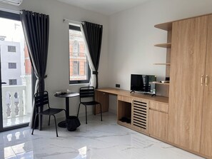 A small, modern room with a desk, two chairs, a television, and a wardrobe.