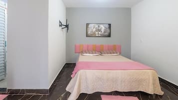 Ein Schlafzimmer mit einem Bett, einem Kopfteil, einer Wandleuchte und einem gerahmten Bild.
