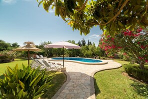 A swimming pool with a stone pathway, lounge chairs, and umbrellas. - Scenic Country Haven With Pool (Pollença)