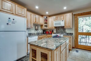 A kitchen with wooden cabinets, a refrigerator, a microwave, and a granite countertop. - Closest Ski-in/out Condo at Northstar Village (Truckee)
