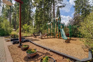 A playground with a slide, climbing structures, and a bench. - Closest Ski-in/out Condo at Northstar Village (Truckee)