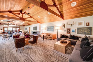 A spacious living area with wooden beams, a fireplace, and various seating arrangements. - Closest Ski-in/out Condo at Northstar Village (Truckee)