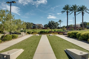 A well-maintained lawn with a central pathway, surrounded by neatly trimmed hedges and palm trees.