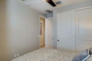 Un dormitorio con una colcha estampada, una puerta blanca y un pasillo que conduce a otra habitación.