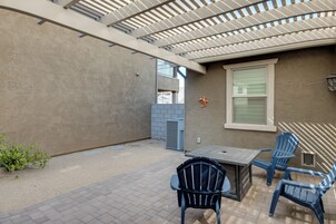 Un área de patio al aire libre con una pérgola, una mesa y dos sillas.