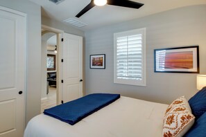 A bedroom with a bed, a ceiling fan, a window with blinds, and a door leading to a closet.