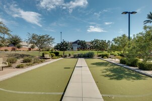 A well-maintained courtyard with a paved walkway, surrounded by greenery and a building in the background.