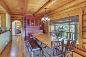 A log cabin interior with a dining area, wooden walls, and a large window. - All-season Family Cabin w/ Forest Views in Truckee (Truckee)