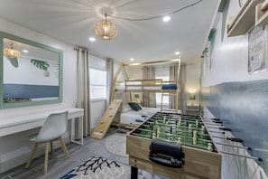 Quarto com beliche, mesa de pebolim, escrivaninha e cadeira.