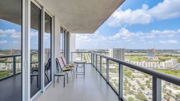 A balcony with a view of a cityscape, including buildings and a construction crane.