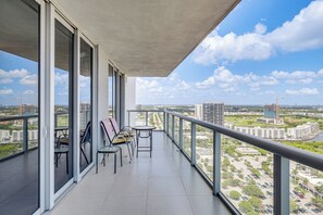 Un balcón con vistas a un paisaje urbano, que incluye edificios y una grúa de construcción.