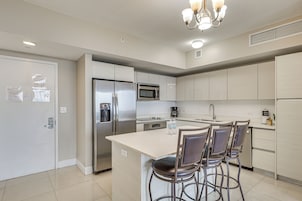 Cozinha moderna com eletrodomésticos de aço inoxidável, uma ilha central com banquetas e um candelabro.