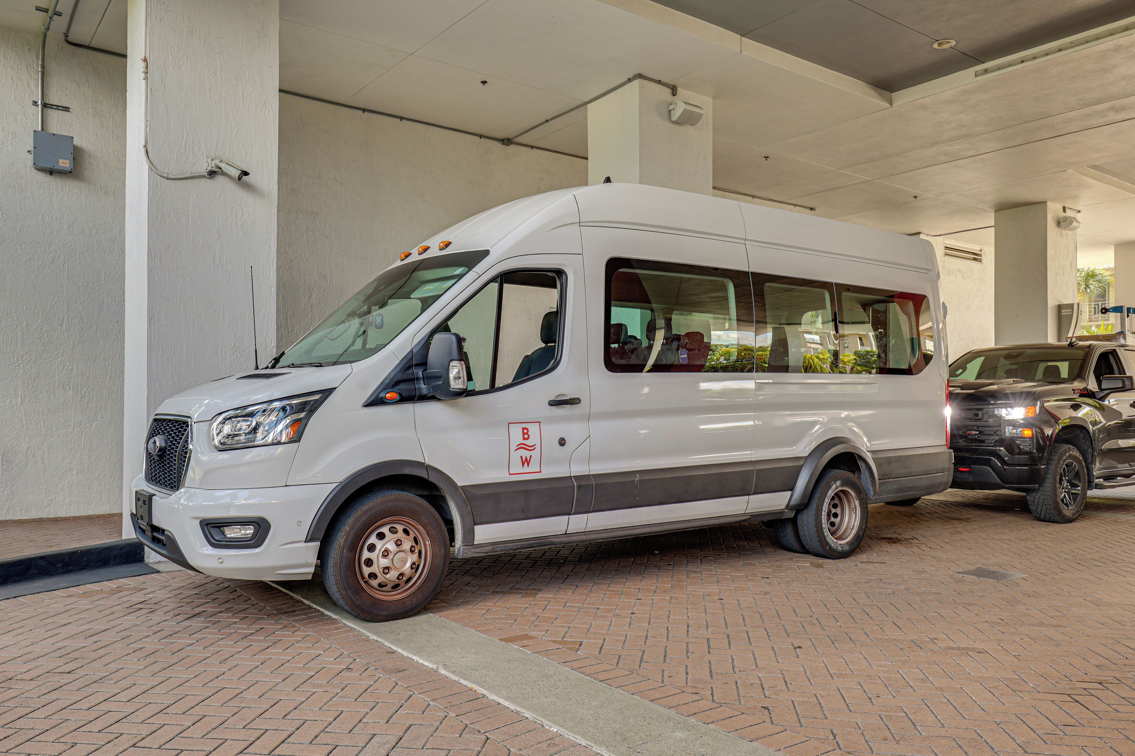 A white van parked in a covered parking area with a brick floor.