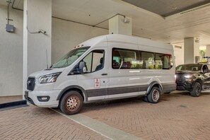 Una camioneta blanca estacionada en un área de estacionamiento techada con piso de ladrillo.