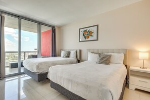 Habitación de hotel con dos camas, un balcón, vistas a la ciudad y una obra de arte enmarcada en la pared.