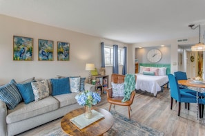 A well-lit living room with a sofa, coffee table, and a dining area with chairs and a table. - Condo w/ Pool & Hot Tub, Short Walk to Beach (Myrtle Beach)