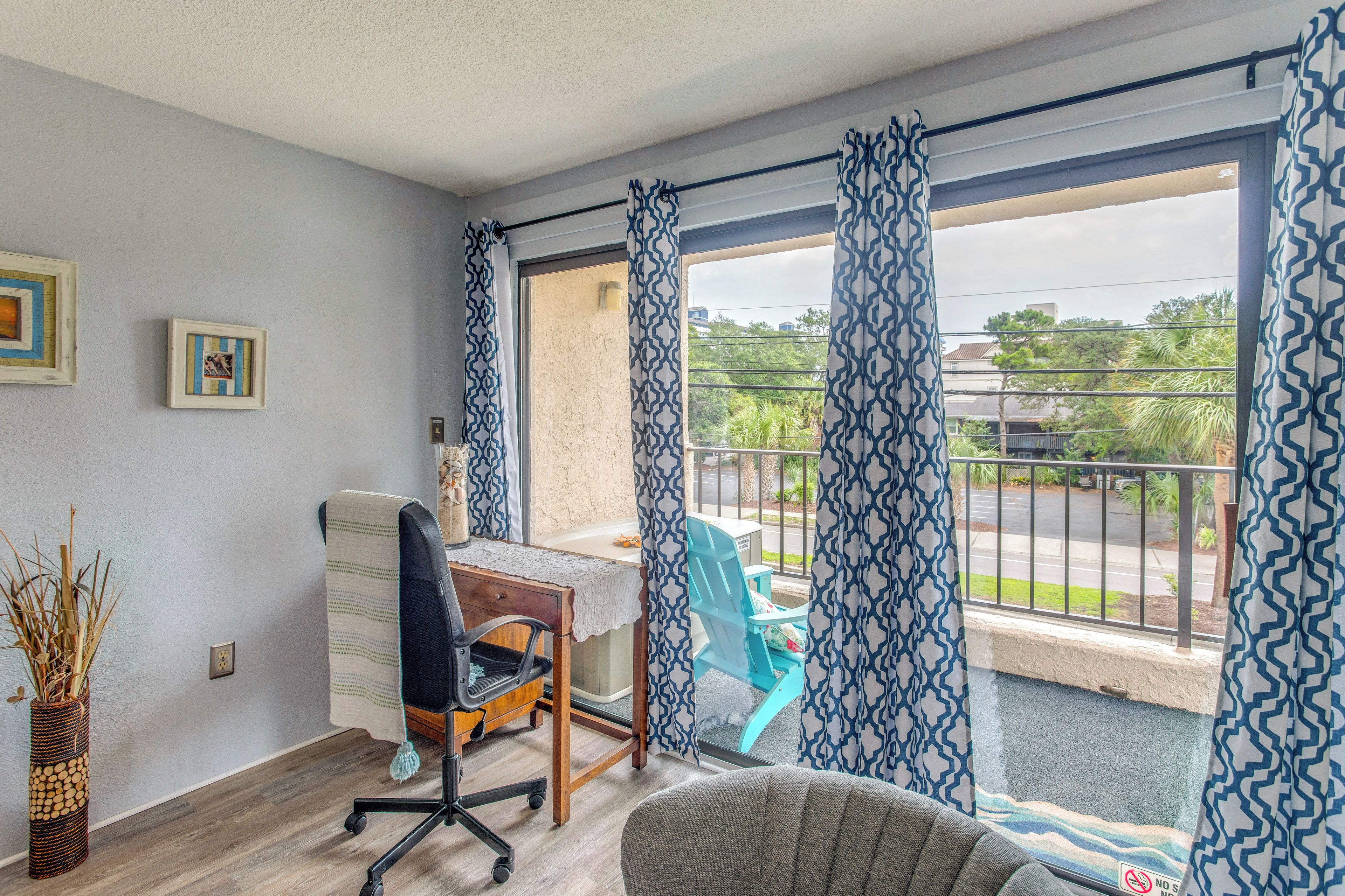 A room with a desk, office chair, and a view of the outside.