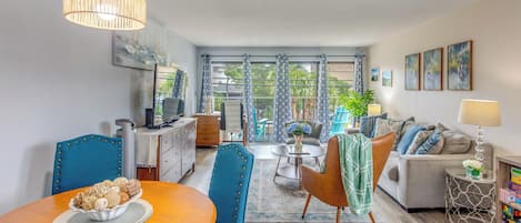 A modern living room with a dining area, featuring a TV, a sofa, and a coffee table.