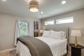 Een slaapkamer met een bed, een bedlampje, een raam en een plafondlamp.