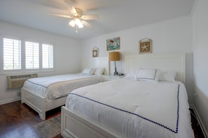 A bedroom with two beds, a ceiling fan, a window with blinds, a wall-mounted lamp, and a framed picture. - Community Pool & Private Patio! N Myrtle Beach Gem (North Myrtle Beach)