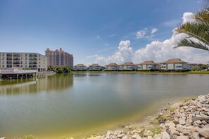 A waterfront property with a calm lake, a bridge, and a row of multi-story buildings with balconies. - Community Pool & Private Patio! N Myrtle Beach Gem (North Myrtle Beach)