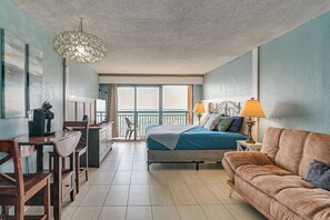 A hotel room with a balcony, a bed, a sofa, a desk with a chair, and a coffee machine. - 14th-floor Ocean View + Pools! Myrtle Beach Haven (Myrtle Beach)