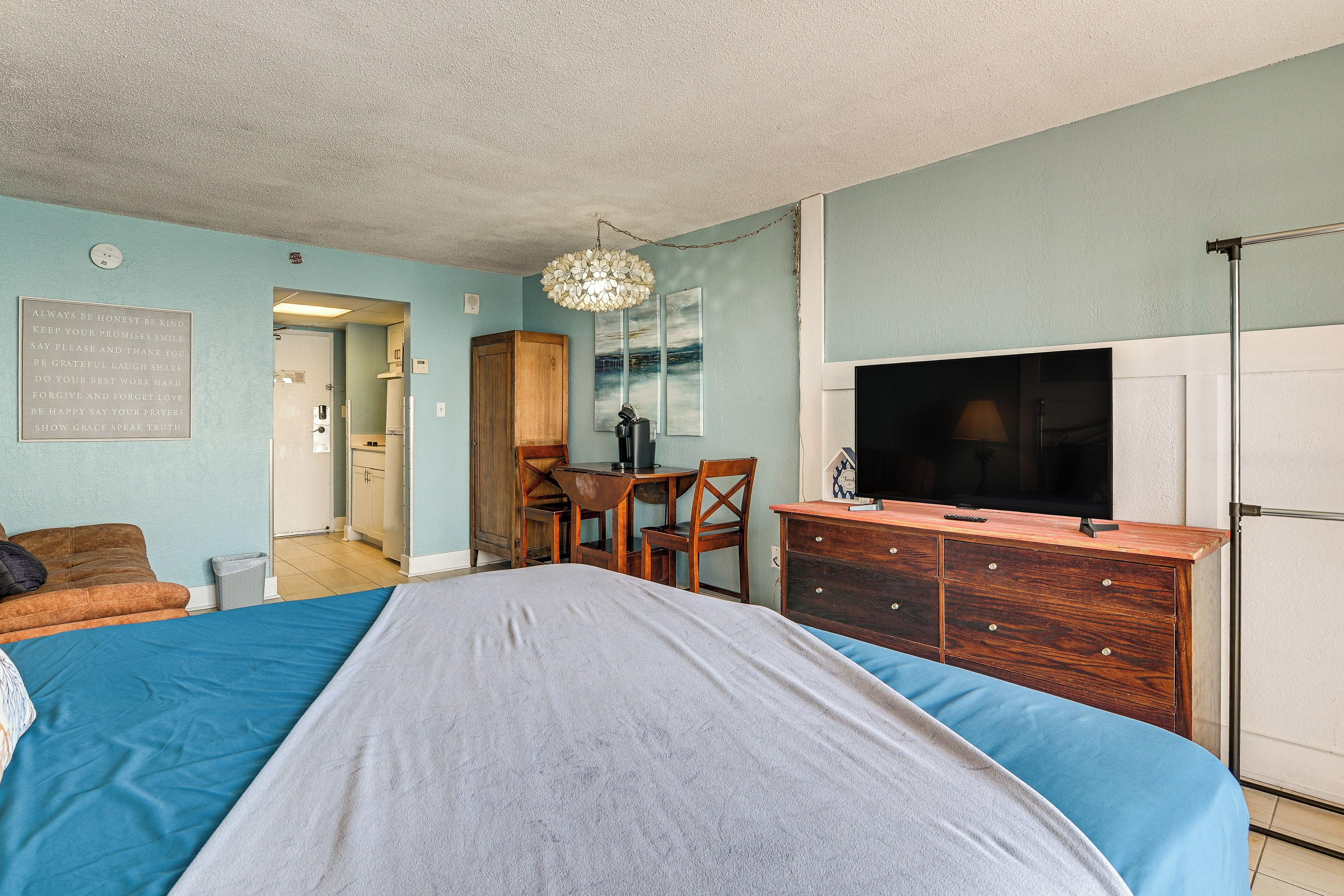 A bedroom with a bed, a desk, a chair, a television, and a wardrobe.