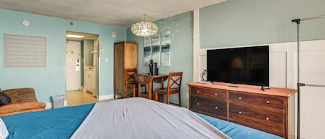 Un dormitorio con cama, escritorio, silla, televisor y armario.
