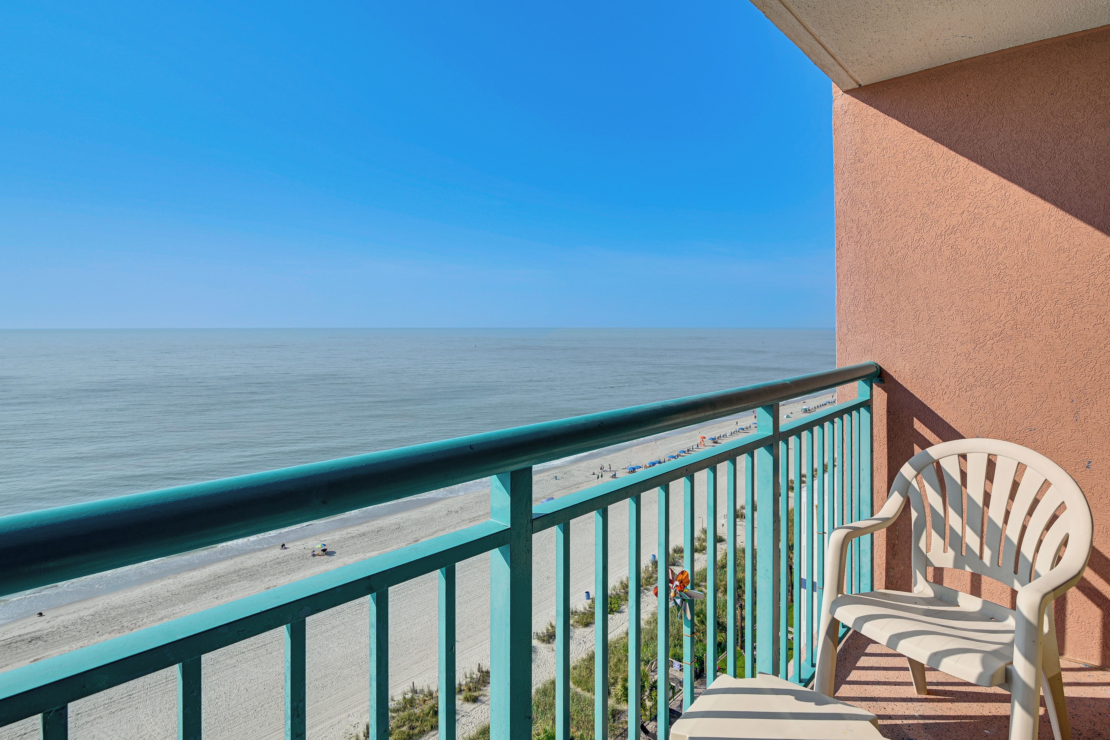 A balcony with a view of a beach and ocean.