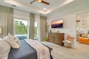 A bedroom with a bed, a dresser, a television, and a view of the outdoors. - Fort Morgan Hideaway Hot Tub Golf Beach Access (Gulf Shores)