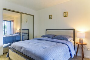 Un dormitorio con una cama grande, una mesita de noche con una lámpara y un espejo.