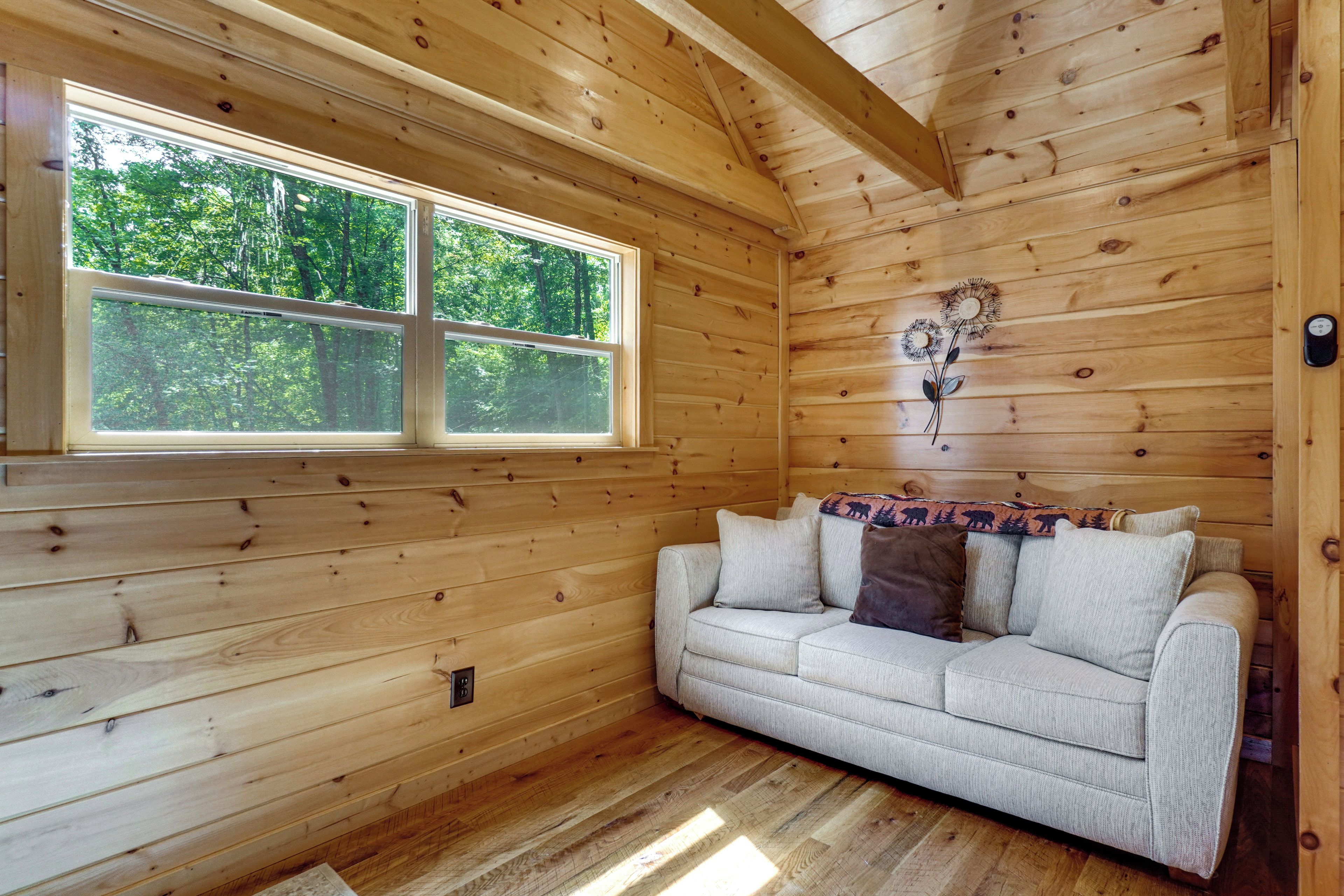 Un interior de madera con un sofá, una ventana y una lámpara de pared.