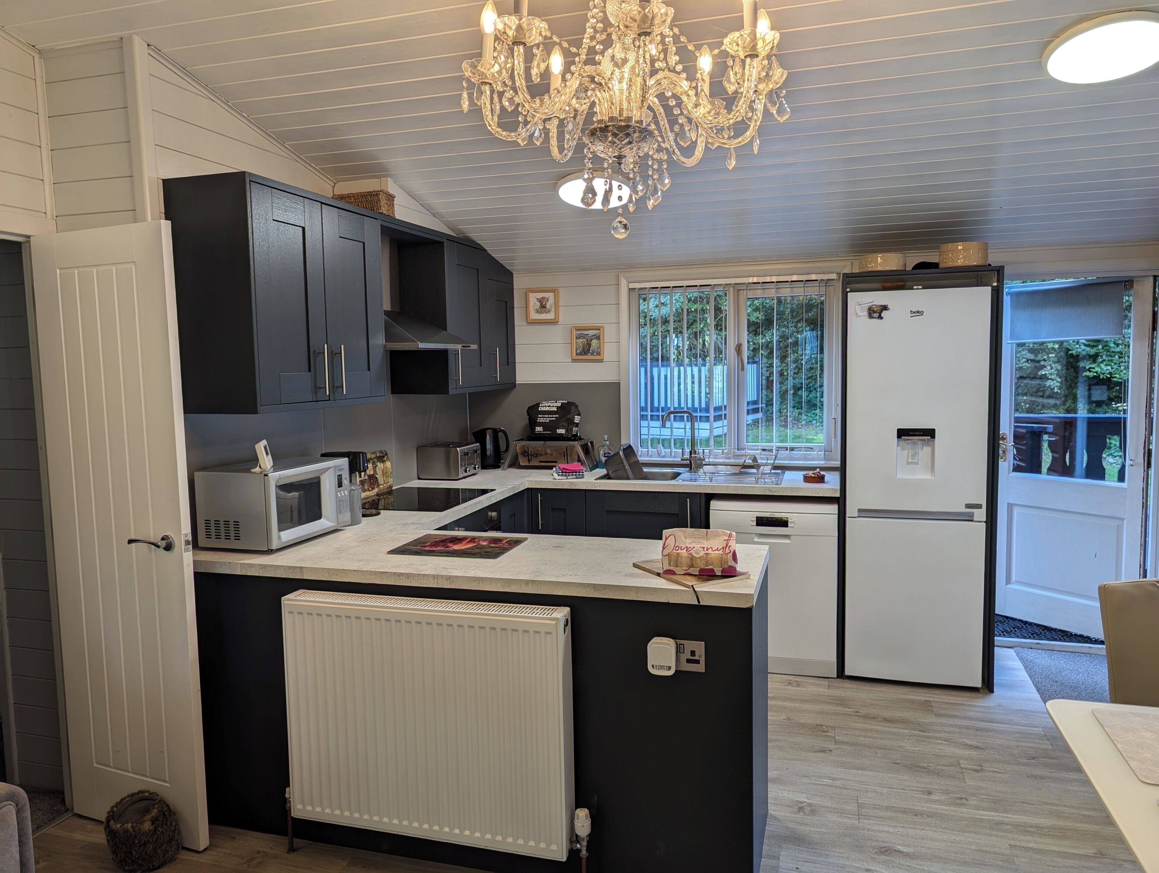 A modern kitchen with a central island, built-in appliances, and a large window providing natural light.