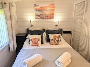 Habitació d'hotel amb un llit, dos llençols amb estampats d'animals, un quadre sobre el llit i una finestra amb cortines.
