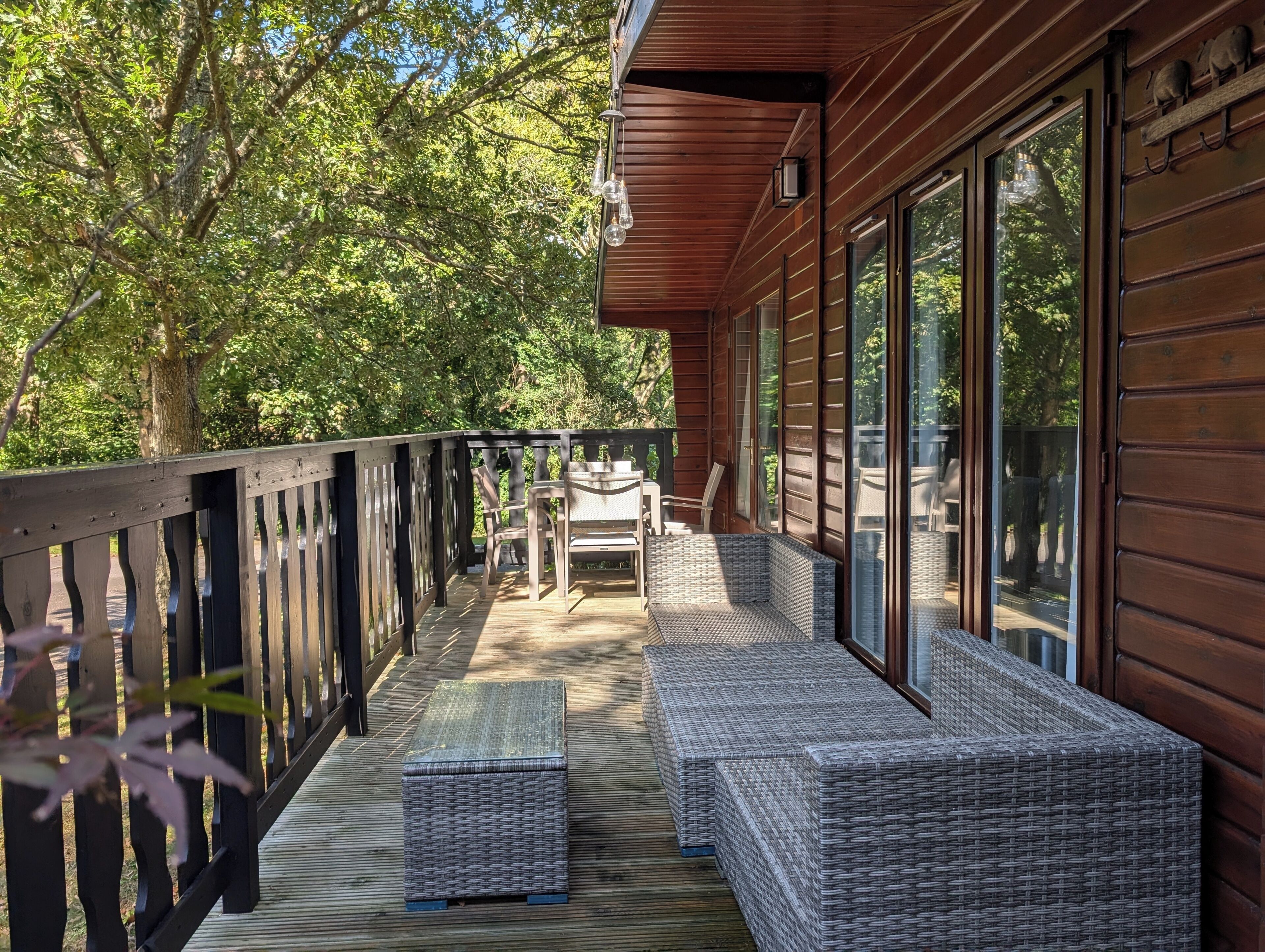 A wooden deck with wicker furniture and a glass door leading to a covered area.